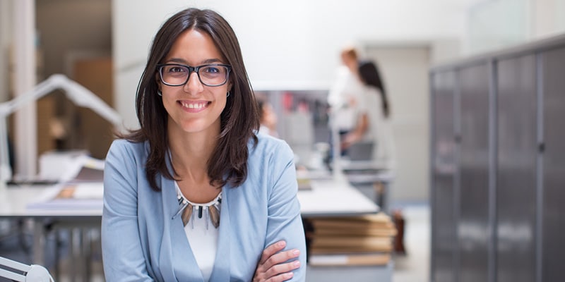 Woman used for Economics for Public Policy course in glasses and blue top and smiling at the camera