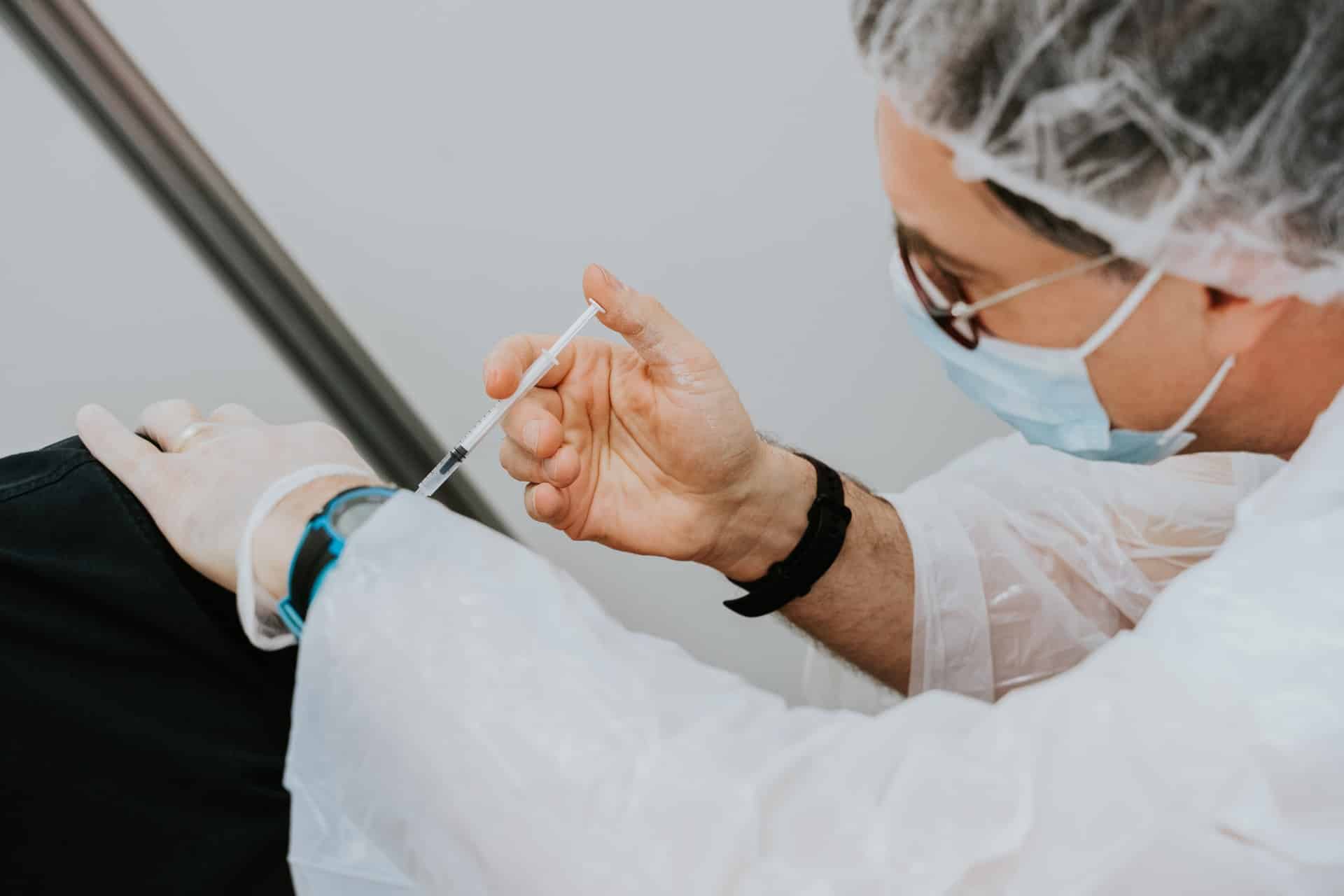 person in personal protective equipment giving a covid-19 vaccination