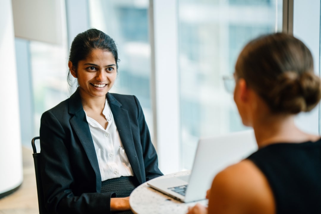 Young smart Indian Asian woman in business meeting with colleague with laptop